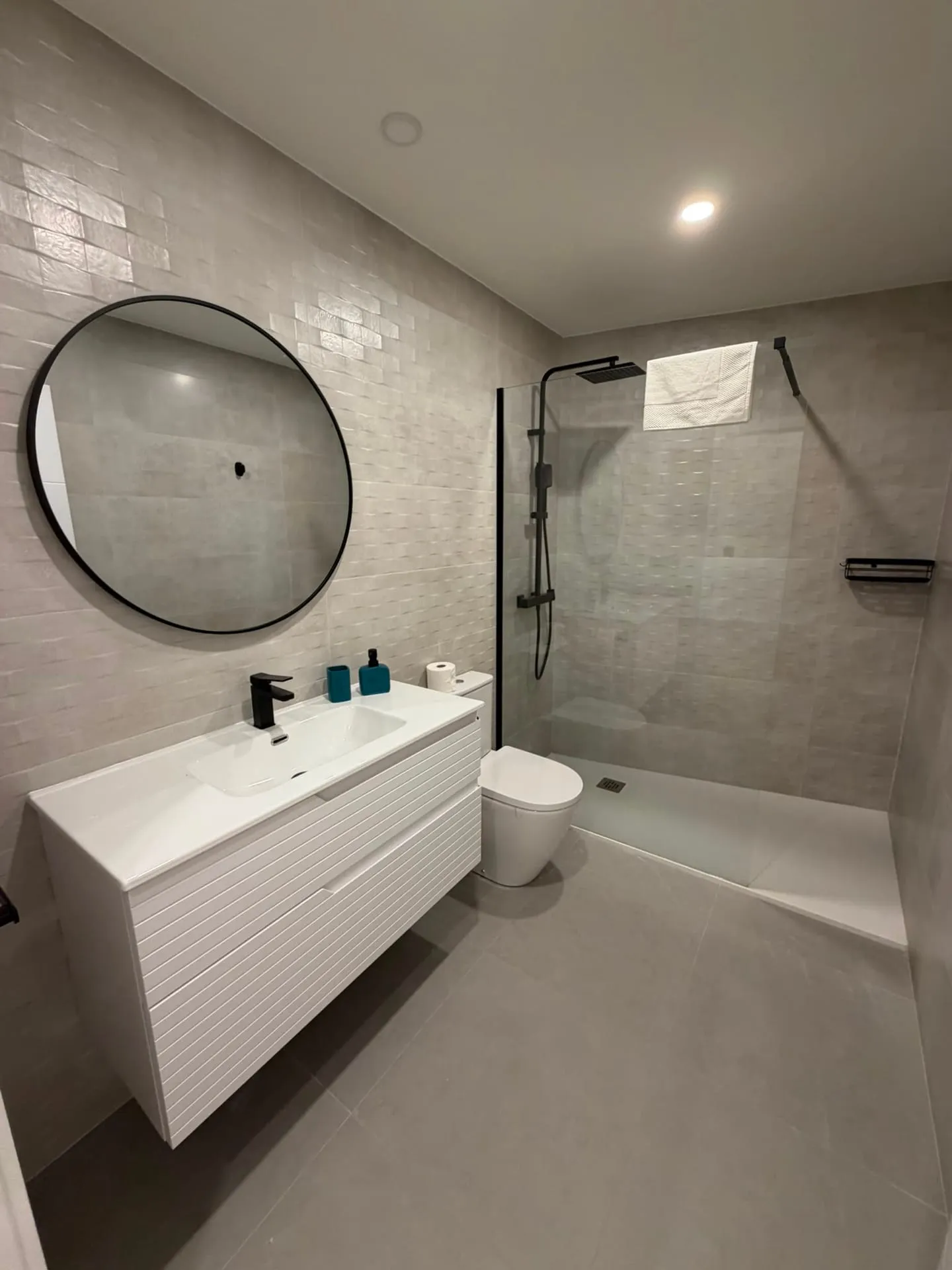 Baño con ducha de obra y espejo redondo